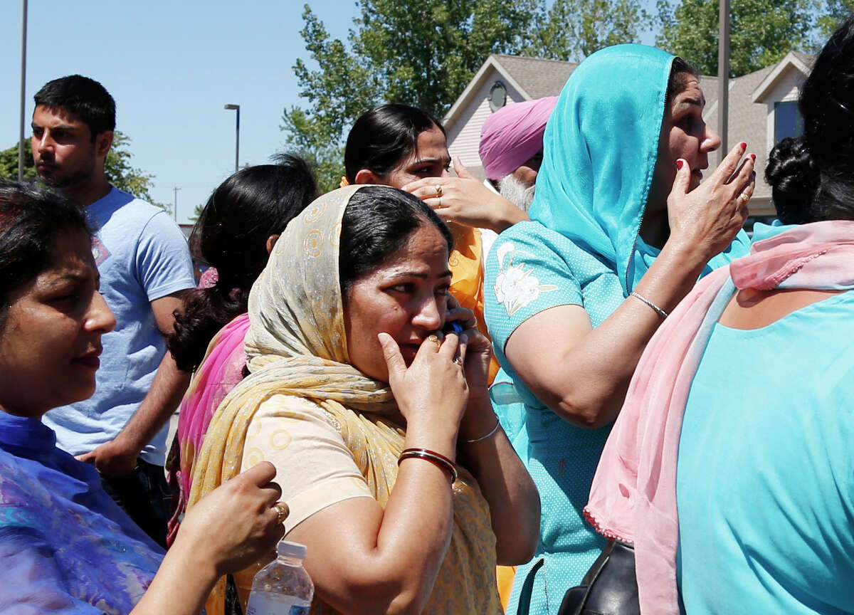 A woman uses a phone as people react outside the Sikh Temple of Wisconsin in Oak Creek, Wi, where a shooting took place Sunday, Aug 5, 2012. (AP Photo/Jeffrey Phelps)