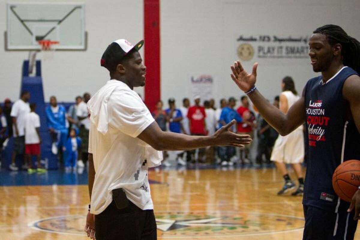Texans wide receiver Andre Johnson shakes hands with Kenneth Faried of the Denver Nuggets while the teams warm up before the Houston Lockout Celebrity Basketball Game game at Delmar Fieldhouse on Sunday, Nov. 20, 2011, in Houston. Johnson watched from the bench as he sat with the NBA players during the game. (Smiley N. Pool / Houston Chronicle)