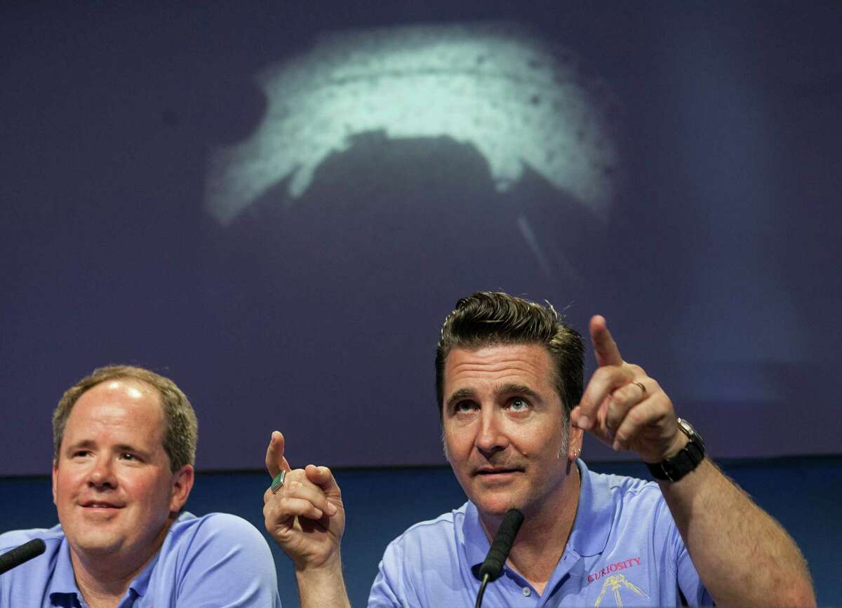 Mars Science Laboratory Curiosity Richard Cook, MSL deputy project manager, left, and Adam Steltzner, MSL entry, descent and landing (EDL) lead, right, point to the first image taken by NASA's Curiosity rover, which landed on Mars the evening of Aug. 5 on the surface of Mars, during a news conference at NASA's Jet Propulsion Laboratory in Pasadena, Calif., Sunday, August 5, 2012. (AP Photo/Damian Dovarganes)