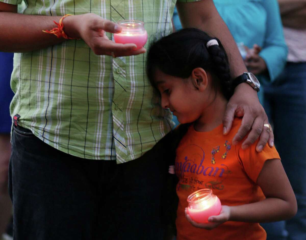 A man holds his child during a candle light vigil for the victims of the Sikh Temple of Wisconsin shooting in Milwaukee Sunday, Aug 5, 2012. An unidentified gunman killed six people at the suburban Milwaukee temple on Sunday in a rampage that left terrified congregants hiding in closets and others texting friends outside for help. The suspect was killed outside the temple in a shootout with police officers. (AP Photo/Jeffrey Phelps)