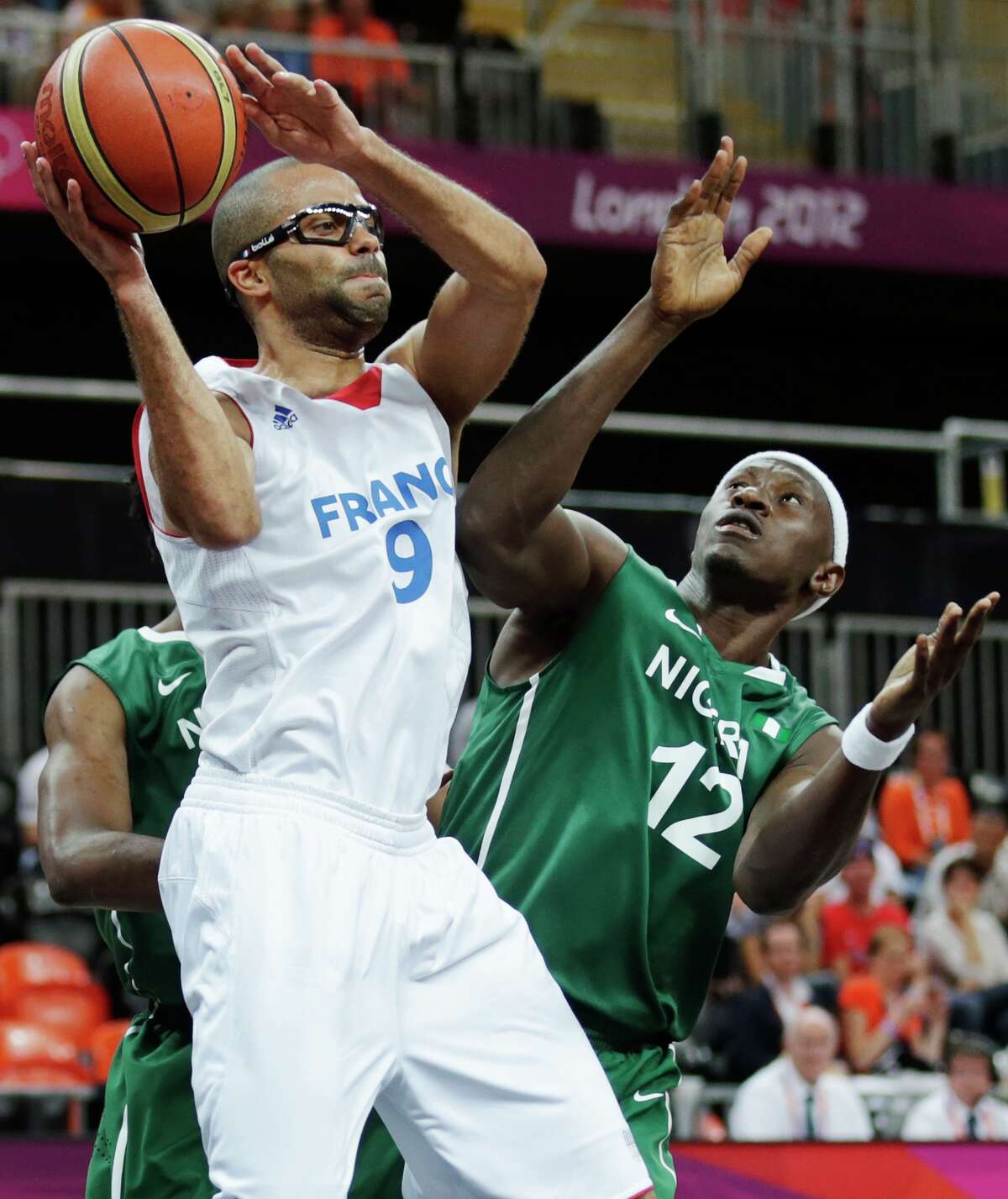 France's Tony Parker looks to pass while being defended by Nigeria's Ejike Ugboaja during a men's basketball game at the 2012 Summer Olympics, Monday, Aug. 6, 2012, in London. (AP Photo/Charles Krupa)