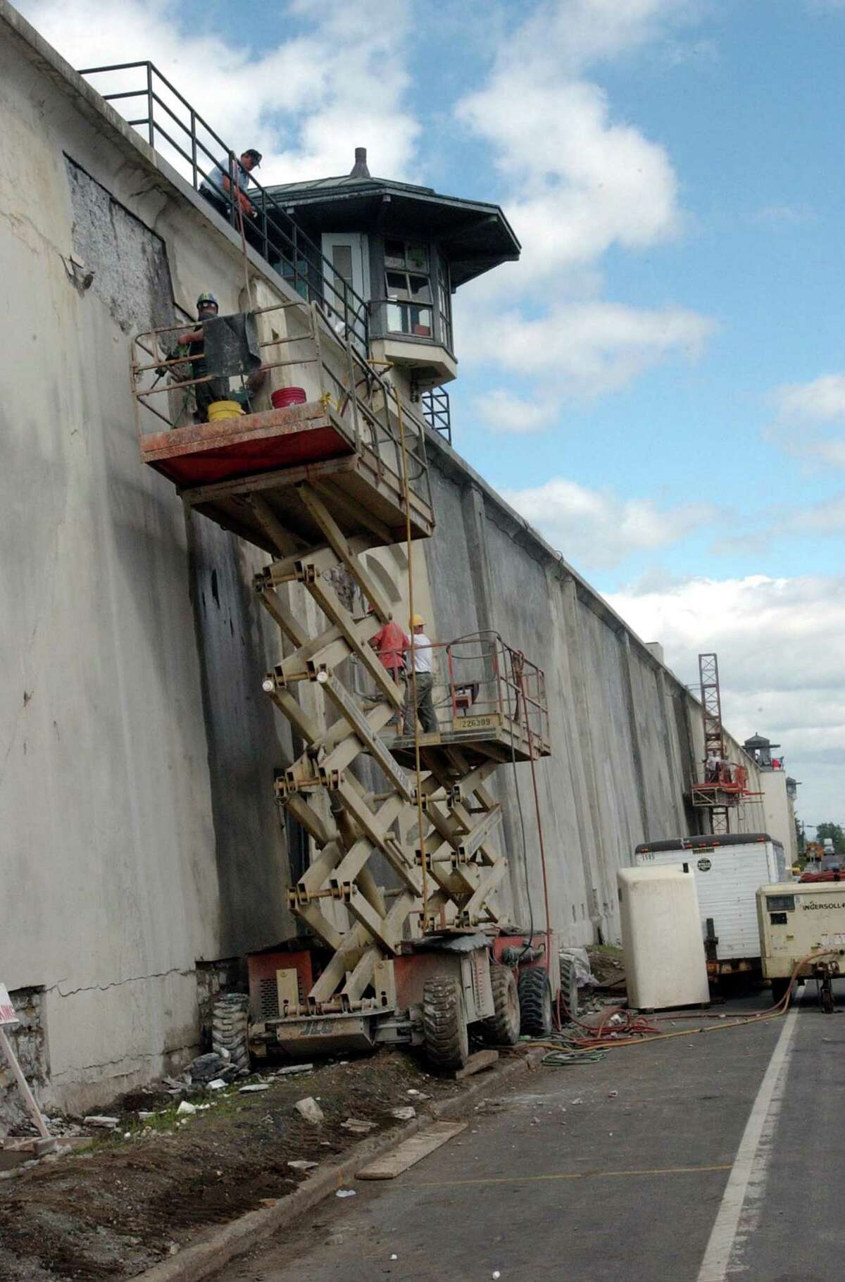 Workers repair a section of Clinton Correctional Facility's historic wall along Cook Street Sunday, Nov. 14, 2004, in Dannemora, N.Y. After four decades of harsh weather rotting the wooden wall and complaints from residents, New York state appropriated $20,000 to replace it with a more imposing barrier made from stones quarried in Dannemora and Lyon Mountain. (AP Photo/Press Republican, Michael Betts)