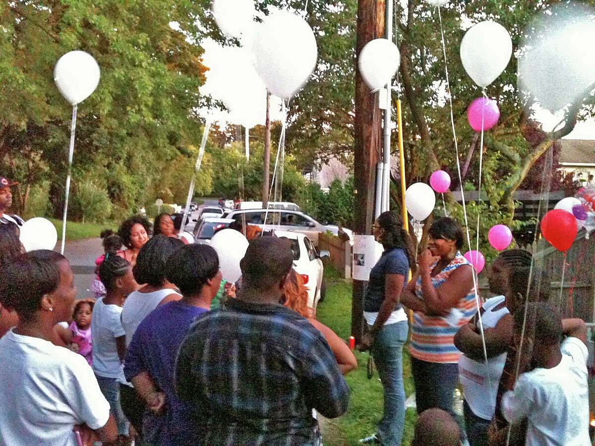 Friends and family members prepare to release pink and white balloons into the air in memory of Rickita Smalls and Iroquois Alston, who were shot to death a year ago Monday in Norwalk, during a remembrance ceremony held a the site of the crime.