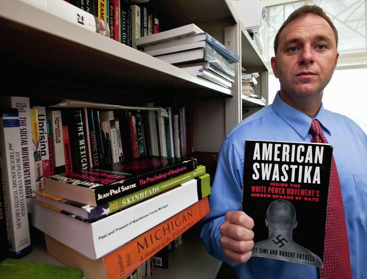 Pete Simi holds his book "American Swastika" while posing for a photo in his office in Omaha, Neb., Tuesday, Aug. 7, 2012. Simi, a professor at the School of Criminology and Criminal Justice at the University of Nebraska-Omaha, has done extensive field research into domestic hate groups, white supremacists and neo-Nazis. He knew Wade Michael Page, the Wisconsin Sikh temple gunman, from field research he did in southern California in 2001-2003 but had since lost touch with him. (AP Photo/Nati Harnik)