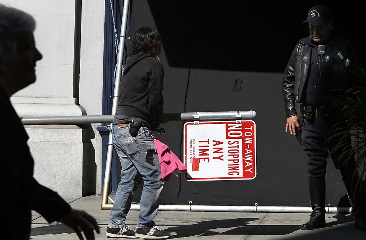 A production assistant carries a street sign that was removed for the filming of Woody Allen's movie at Shreve and Co. jewelers at Post Street and Grant Avenue in San Francisco, Calif. on Friday, Aug. 10, 2012.