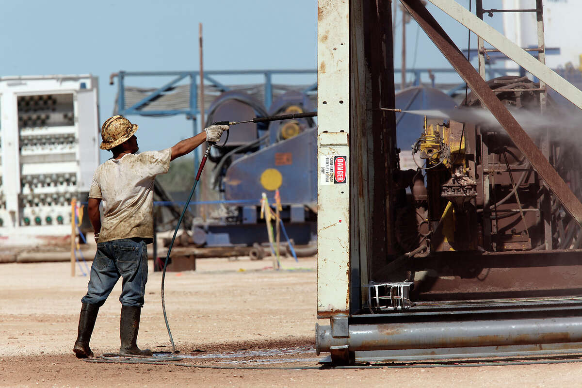 A roustabout worker washes a drilling rig at a lease off Loving County Road 408 near Mentone, Texas, Wednesday, July 25, 2012. Located 130 miles west of Midland, Texas, the county has a permanent population of about 85. Around 1,000 to 1,500 people work the oil fields in the county during working hours. The county has no paved county roads according to County Judge Skeet Jones. In the last four years, the county has spent $350,000 a year maintaining them.