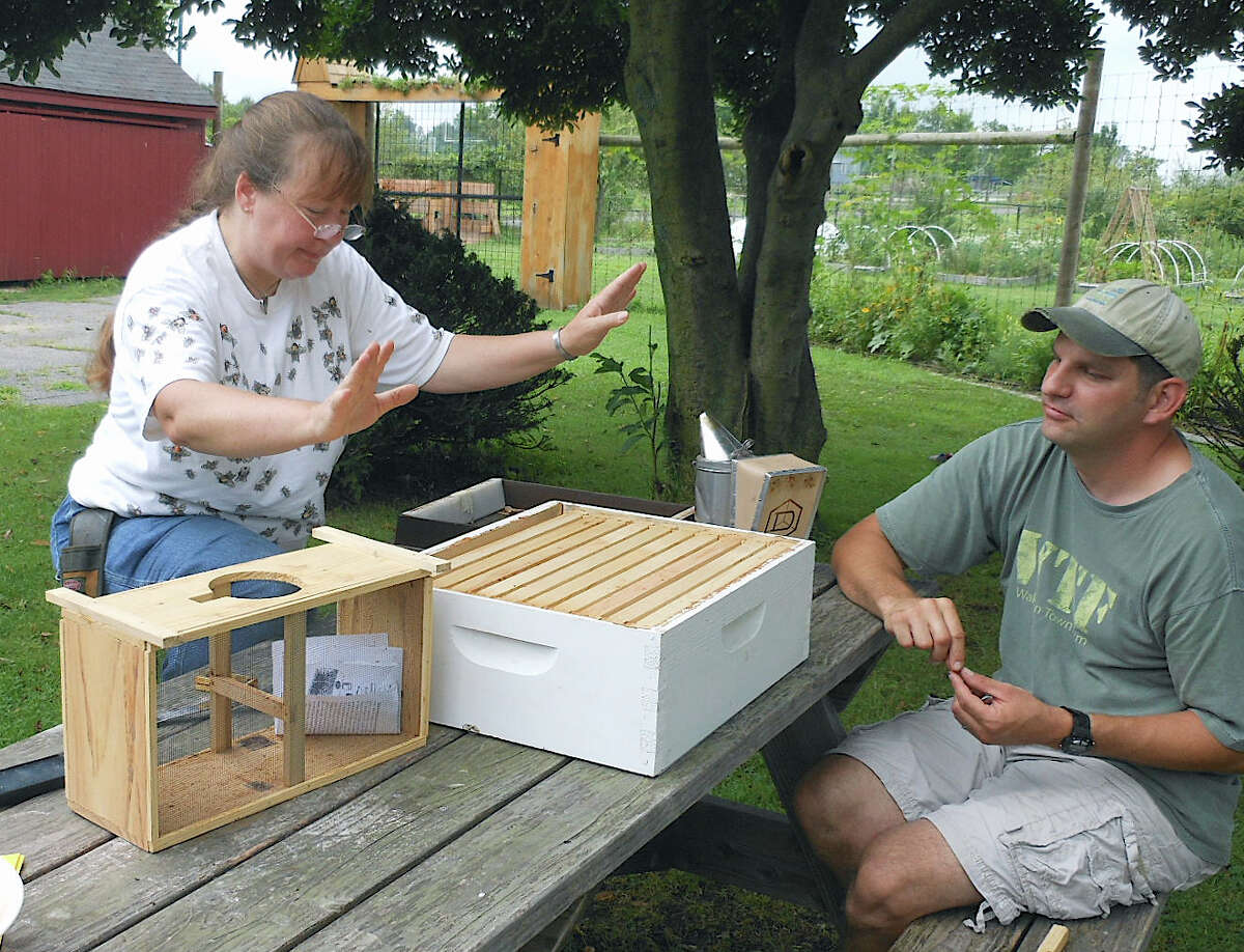 Beekeeper Leslie Huston of Bee Commerce at Wakeman Town Farm Saturday morning, leading a beekeeping workshop, as Mike Aitkenhead, the farm manager, looks on.