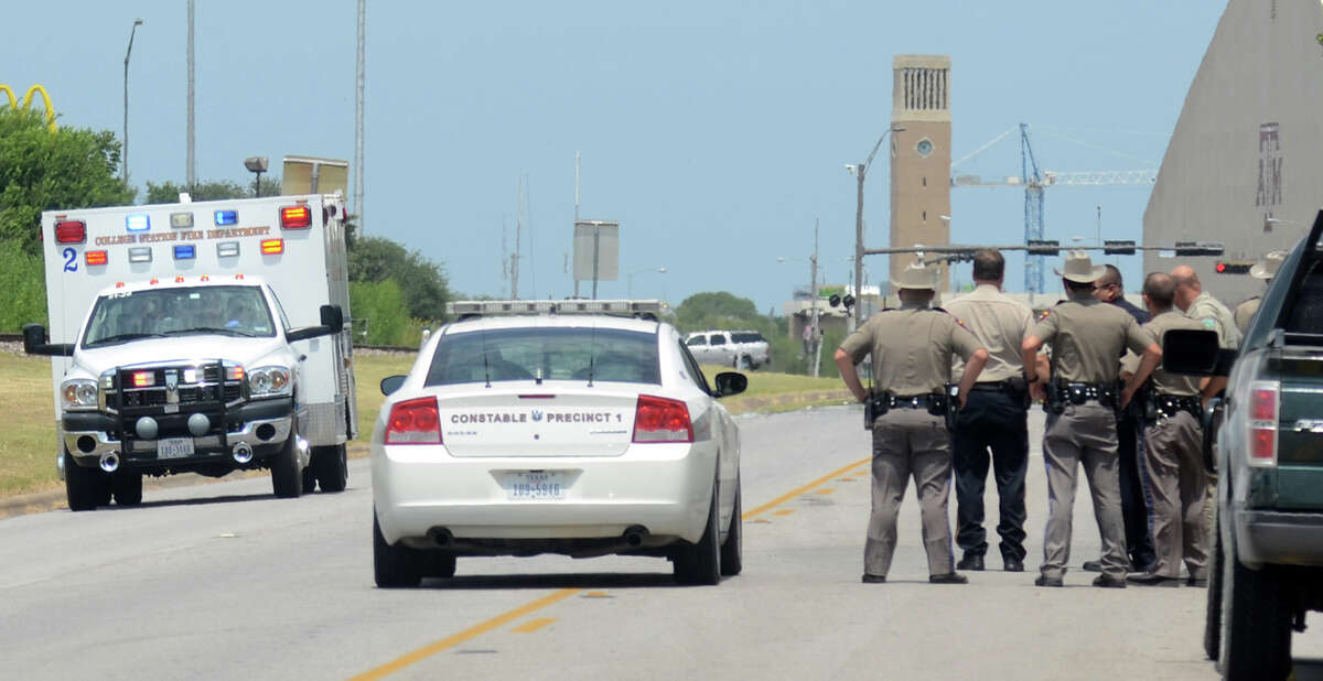 Texas State troopers and Brazos Valley lawmen watch as an ambulance believed to be carrying one of their downed fellow officers speeds off to a hospital in College Station, Texas, Monday, Aug. 13, 2012. Police say at least one law enforcement officer and one civilian have been killed in a shooting near Texas A&M University's campus. Assistant Chief Scott McCollum says the gunman also was shot Monday before being taken into custody. (AP Photo/Bryan-College Station Eagle, Dave McDermand)