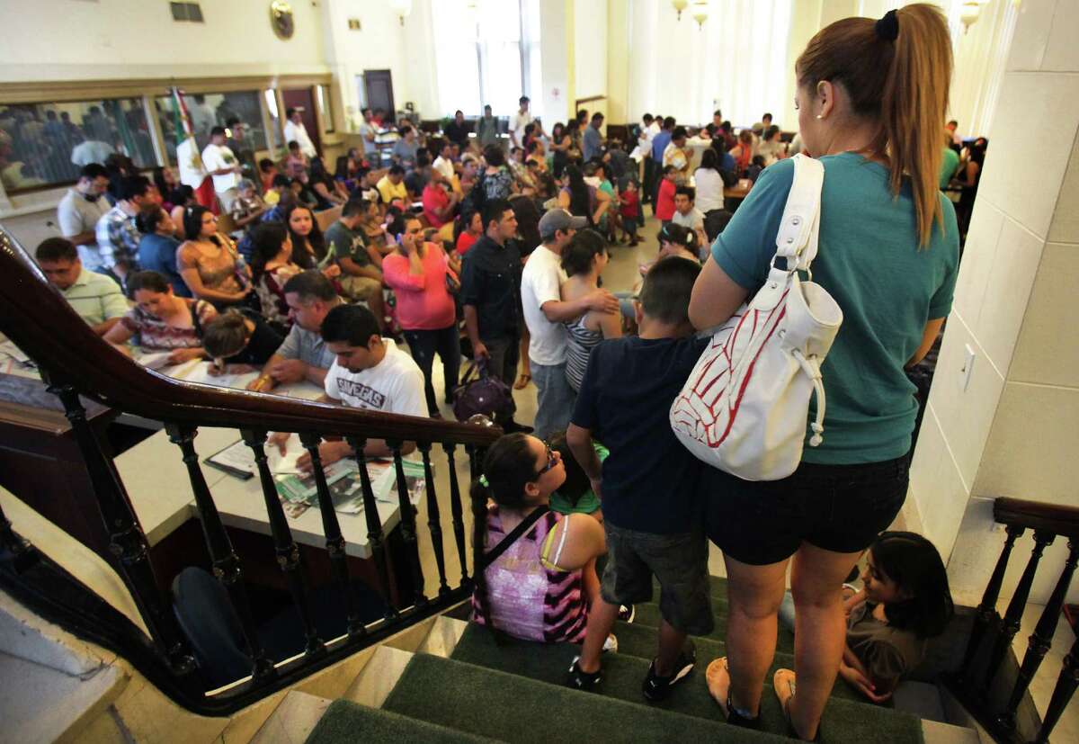 An unidentified boy walks down stairs with his mother to the lobby of the Mexican Consulate in San Antonio where close to 200 wait to complete necessary identification documents to secure immigration status. Tuesday, August 14, 2012.