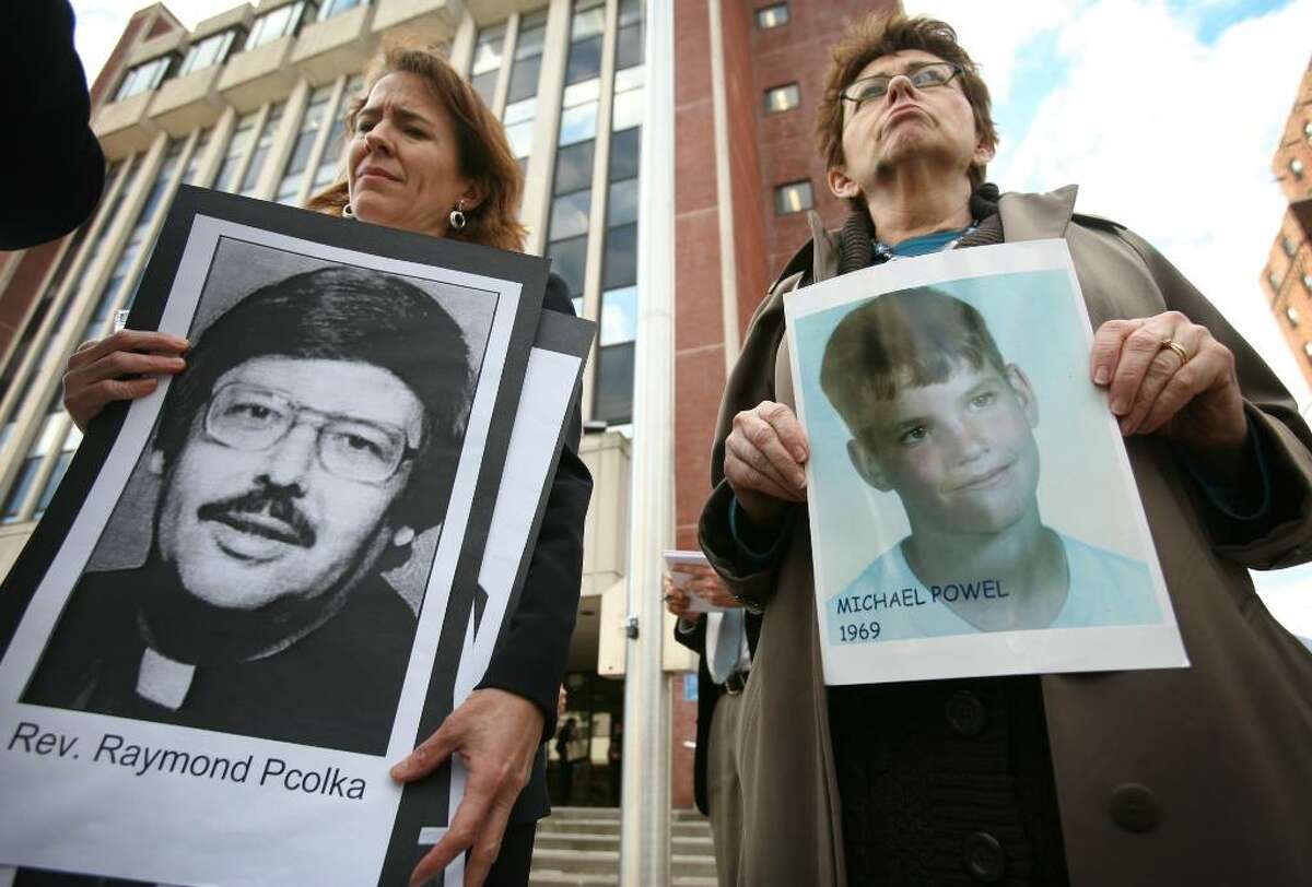 (FILE) Anne Barrett Doyle, left, co-director of Bishop Accountability.org, holds a photo accused priest Raymond Pcolka, and abuse victim Gail Howard of Norwalk holds a photo of fellow victim Michael Powel, at a protest outside Bridgeport Superior Court in December 2009.