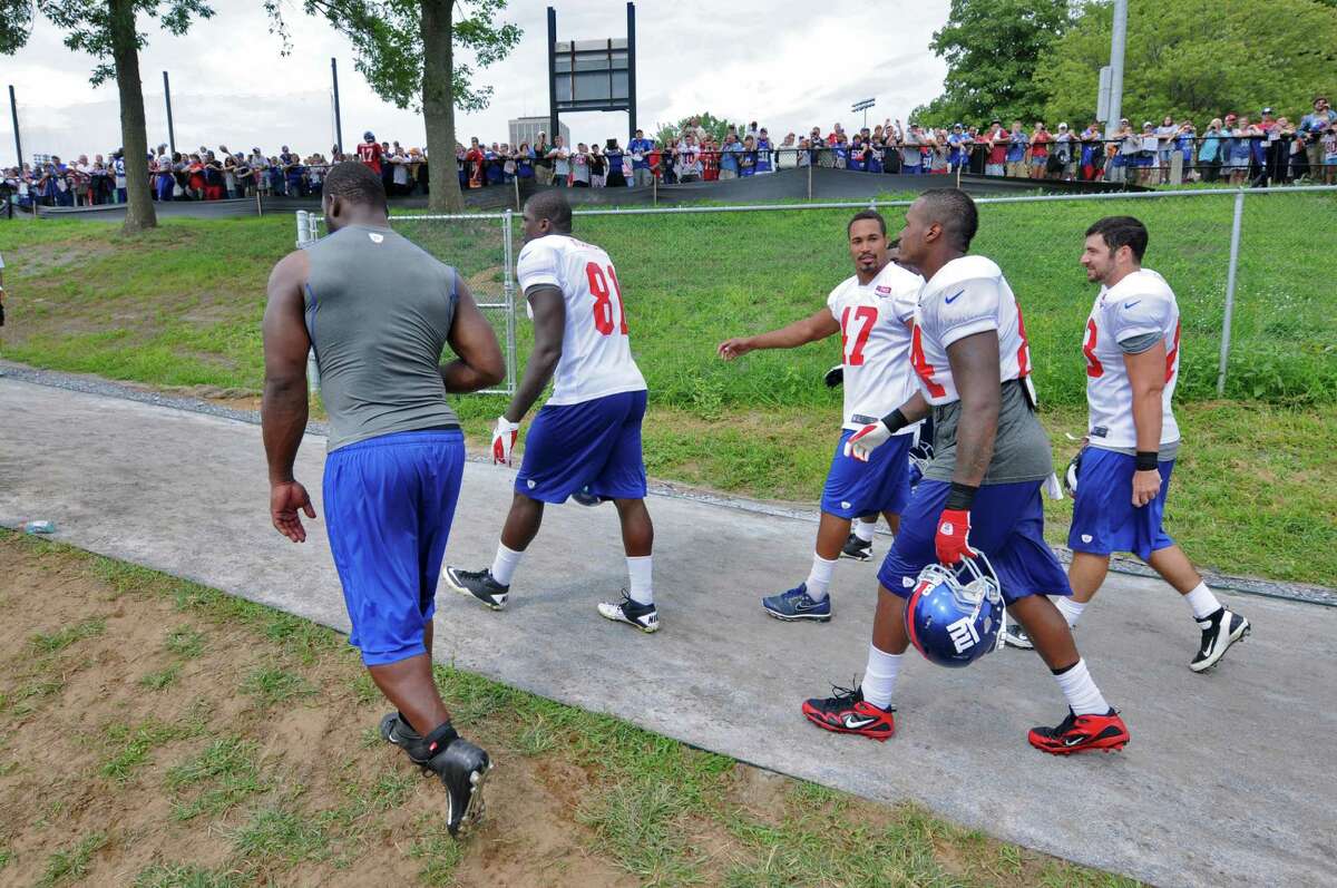 New York Giants players Justin Tuck, Adrien Robinson, Travis Beckum, Christian Hopkins and Joe Martinek, left to right, walk off the field as fans wait for autographs at the end of practice on the last day of training camp at UAlbany on Tuesday Aug. 14, 2012 in Albany, NY. (Philip Kamrass / Times Union)