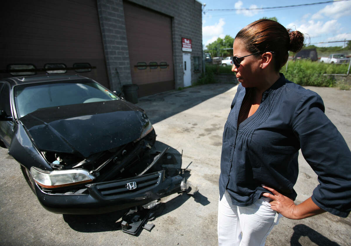 Mireya Porto of Bridgeport looks at her car, a 2002 Honda Accord, that was totalled in an accident with Bridgeport state representative candidate Christina Ayala on North Avenue in Bridgeport on Wednesday. Porto's daughter, Krystal Velez, was driving the car.