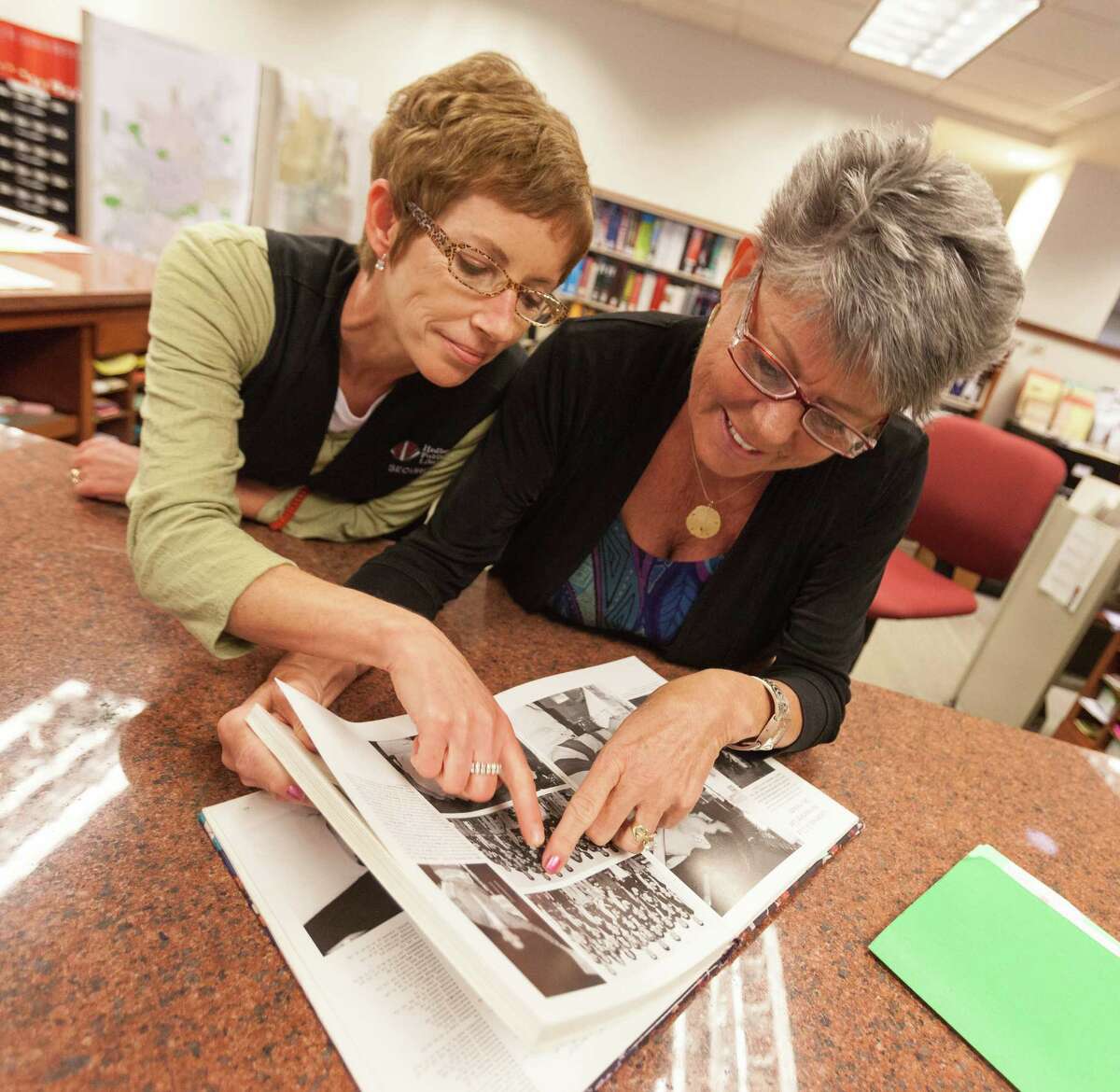 In this photo taken Aug. 12, 2012, librarians Jennifer Spangler, left, and Carolyn Messer, look at photos of Republican Vice Presidential candidate, Rep. Paul Ryan, R-Wis. in his 1988 high school year book at the Janesville Library in Janesville, Wis. A defining moment for Paul Ryan's hometown came at the height of the Great Recession: General Motors, after nearly a century of making Chevrolets on the banks of the Rock River, shut down its oldest assembly plant and erased 6,000 jobs. A defining question for the campaign Paul Ryan joined this week as the Republican Party's vice presidential nominee just might be what comes next for places like Janesville. (AP Photo/Andy Manis)