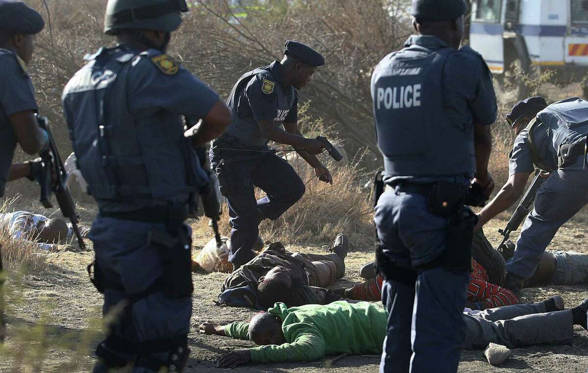Police examine the bodies of striking miners in the aftermath of a battle Thursday in which the officers opened fire on the workers at the Lonmin Platinum Mine near Rustenburg, South Africa.