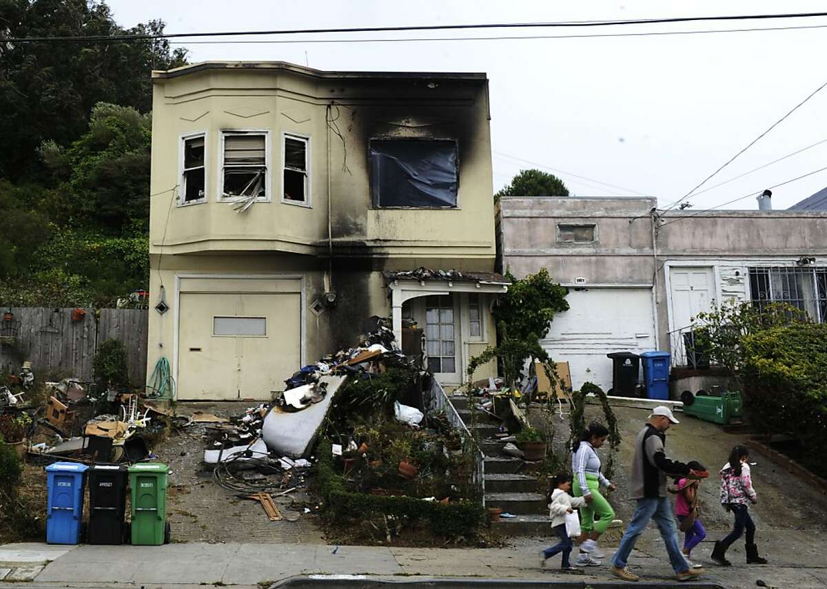 The Arciga Duenas family walks past the house that has been in fire on Friday, Aug 17, 2012 in San Francisco, Calif.
