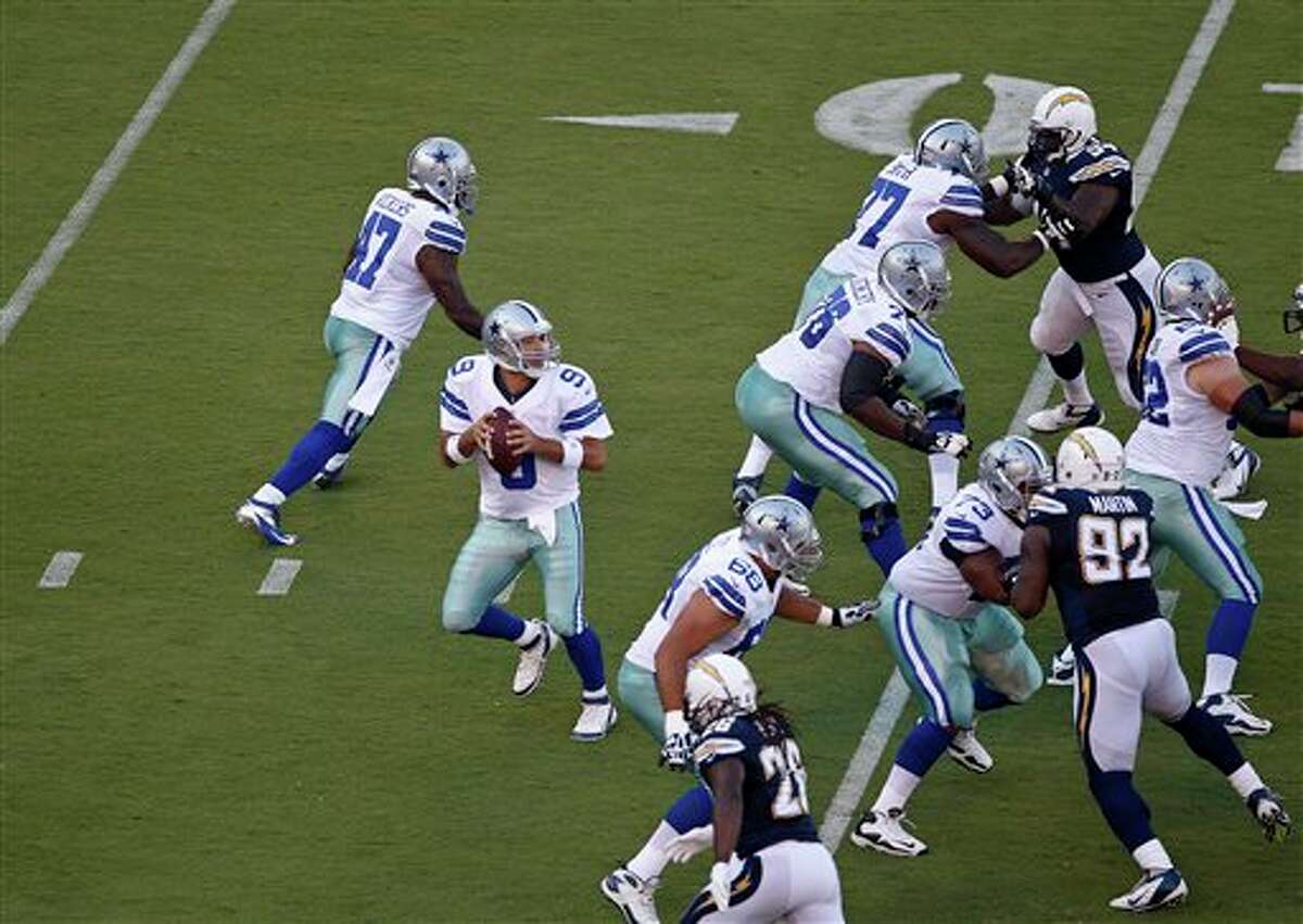 Dallas Cowboys quarterback Tony Romo stands behind the protective wall of his offensive line as they block the rush of the San Diego Chargers during the first quarter of a NFL preseason football game Saturday, Aug. 18, 2012 in San Diego. (AP Photo/Lenny Ignelzi)