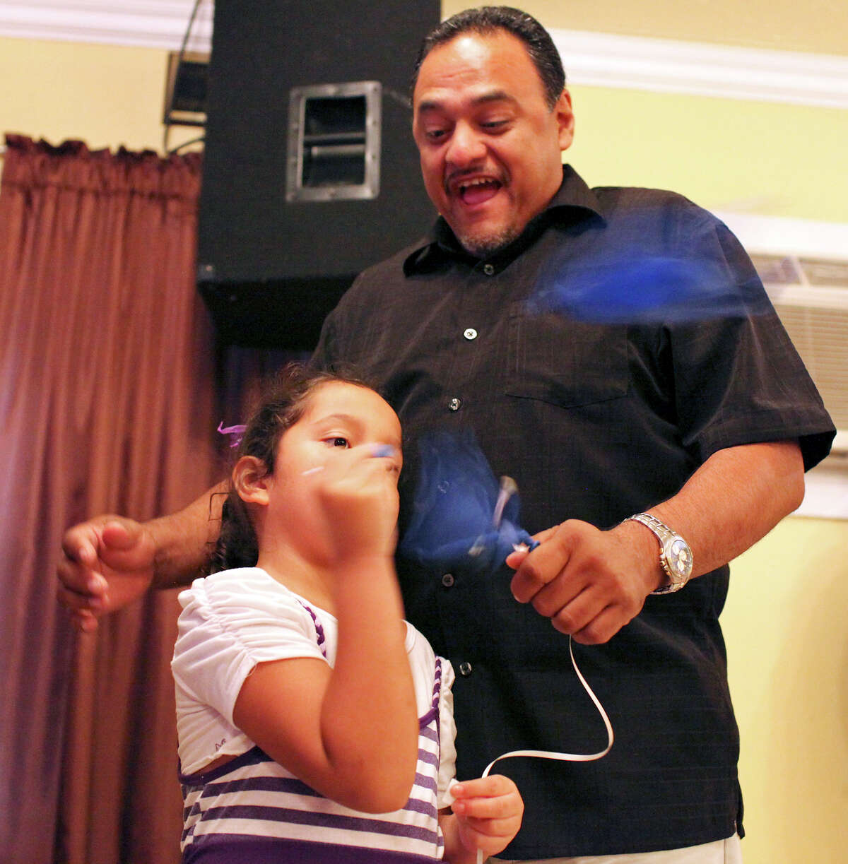 Ernest Alvarado (top) reacts as his daughter Alisandra Alvarado, 5, pops a balloon with money inside during a service held Sunday Aug. 19, 2012 at the River Worship Center. They each found $20 in balloons.