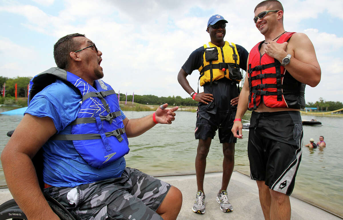 Veteran Sean Michaud (left) shares a laugh with volunteers Terrence Lowe (middle) and Hunter Arnold as they help with All Can Ski, a waterskiing clinic for people with disabilities, at SeaWorld on August 21, 2012.