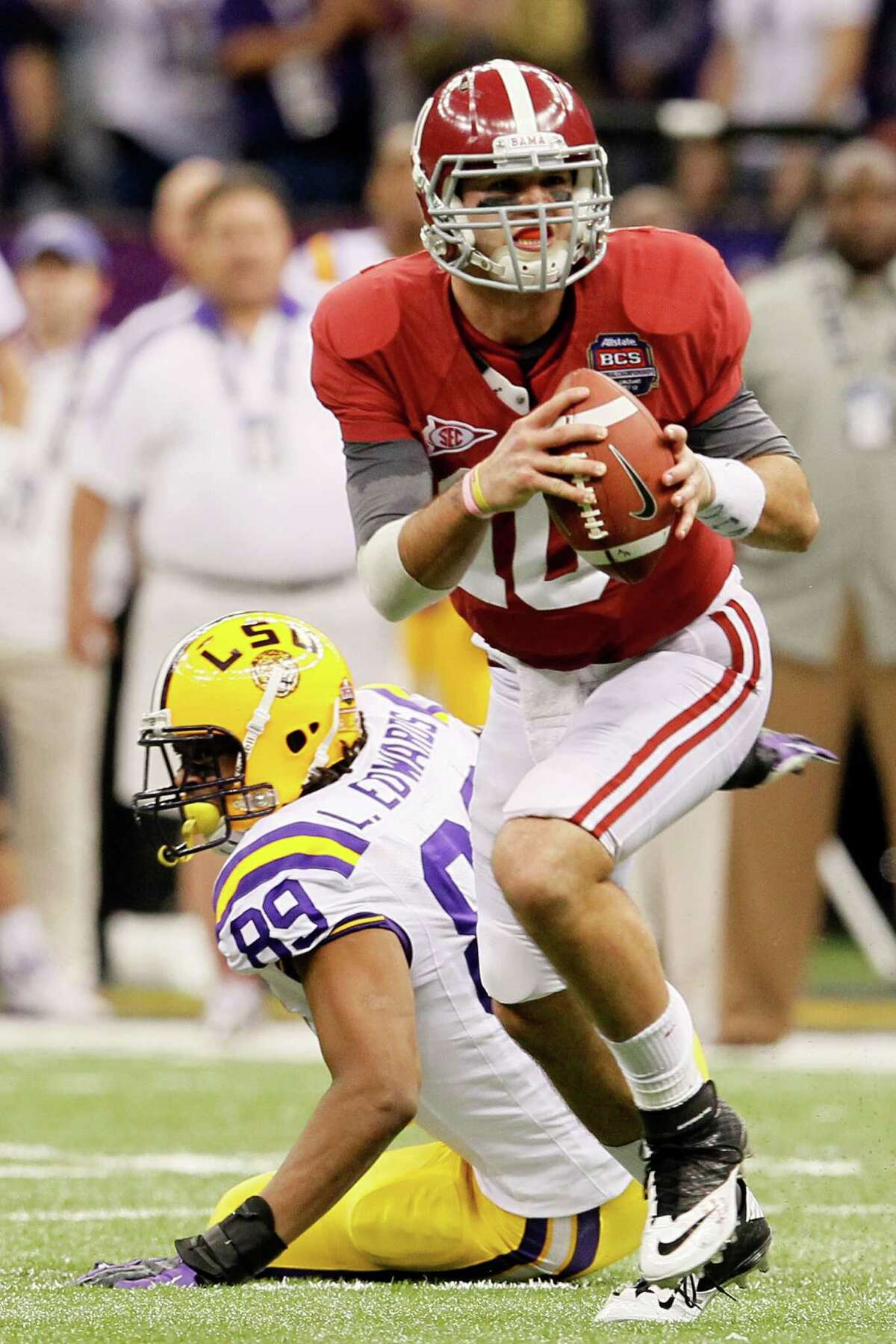 NEW ORLEANS, LA - JANUARY 09: AJ McCarron #10 of the Alabama Crimson Tide runs with the ball against Lavar Edwards #89 of the Louisiana State University Tigers during the 2012 Allstate BCS National Championship Game at Mercedes-Benz Superdome on January 9, 2012 in New Orleans, Louisiana.