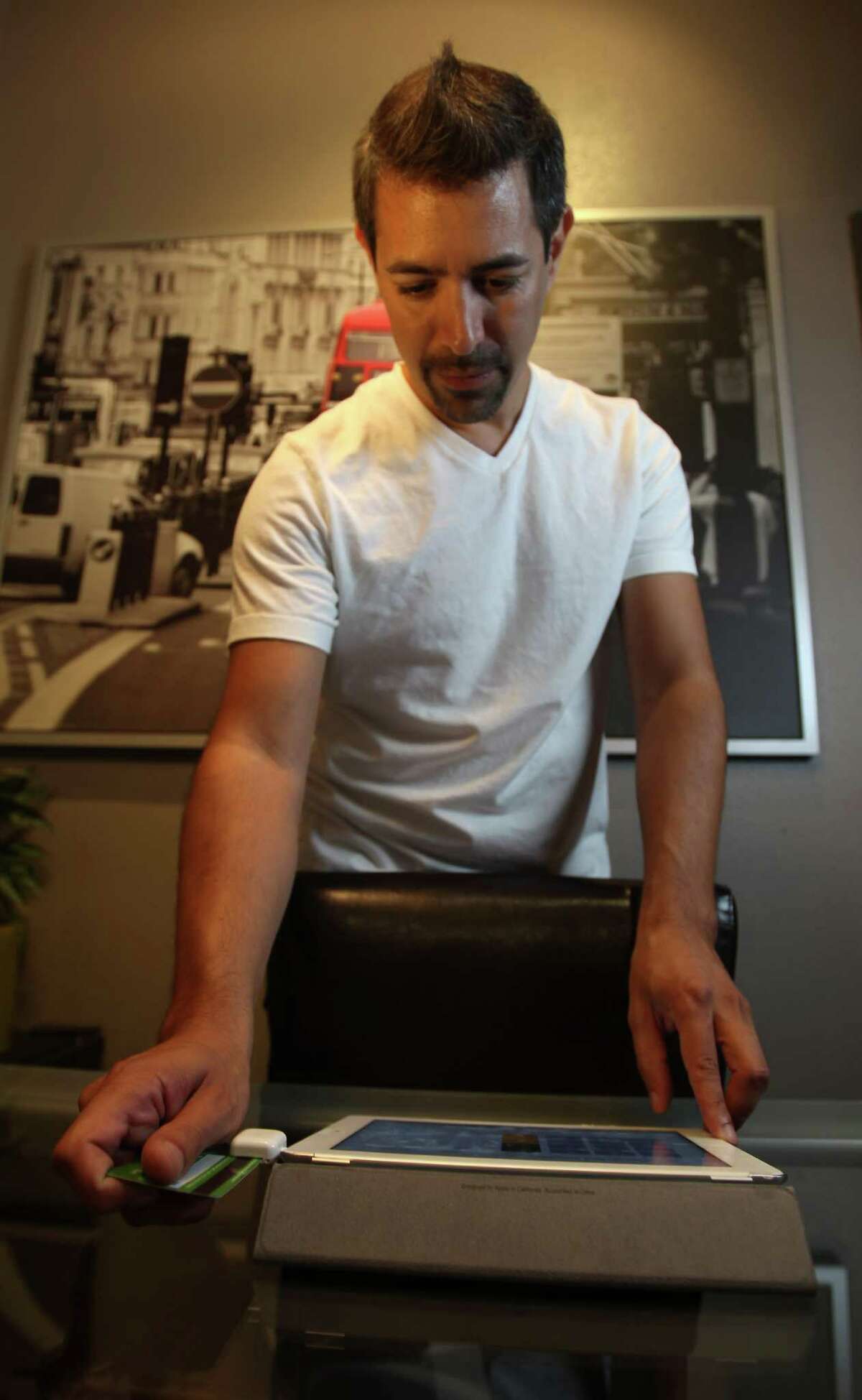 Joey Garza, owner of Urban Therapy, in the Heights, swipes a client's credit card using a Square on his iPad, Monday, Aug. 20, 2012, in Houston. ( Karen Warren / Houston Chronicle )