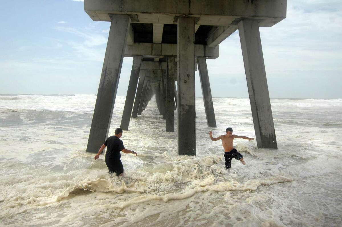 Two teenagers play in the surf under the Navarre Beach Fishing Pier in Navarre, Fla., Tuesday, Aug. 28, 2012 as Isaac approaches the Gulf Coast. Isaac became a hurricane that could flood the coasts of four states with storm surge and heavy rains on its way to New Orleans, where residents hunkered down behind levees fortified after Katrina struck seven years ago this week.