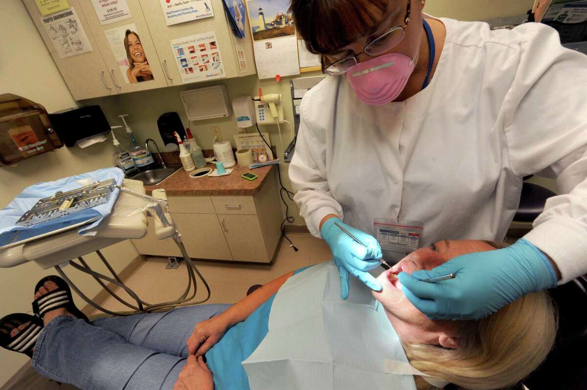 Dental hygienist Elise Lemay takes a look at Kim Schulenburg's teeth at Hometown Health in Schenectady, NY Friday Aug. 24, 2012. (Michael P. Farrell/Times Union)