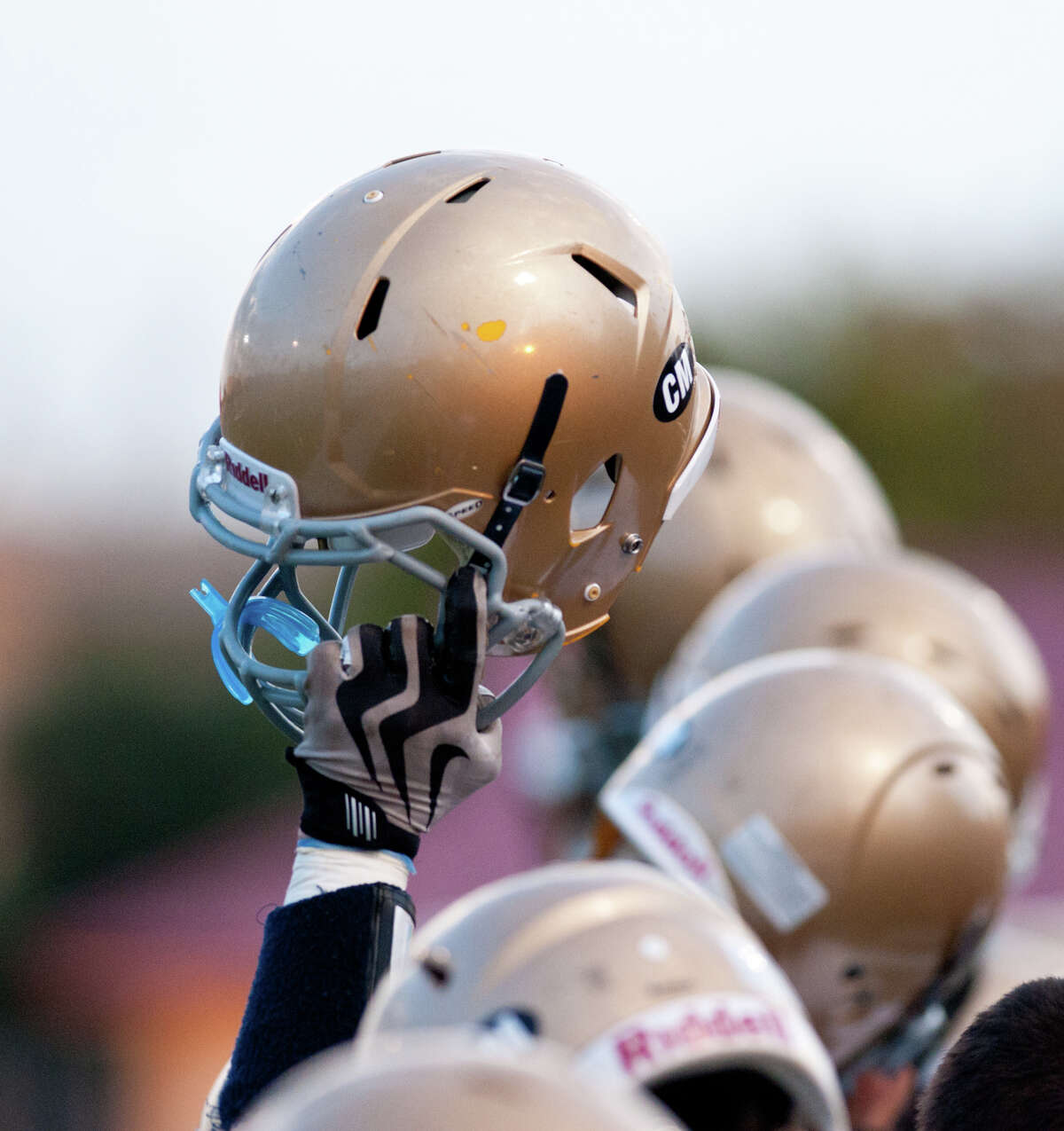 Holy Cross players raise their helmets prior to their game against Central Catholic.