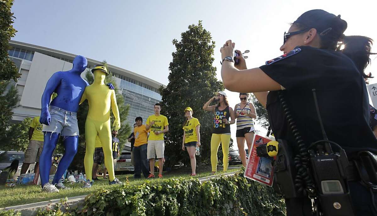 David and David, no last name given, pose for police officer taking a photo outside of Cowboys Stadium before the NCAA college football game between Alabama and Michigan in Arlington, Texas, Saturday, Sept. 1, 2012. (AP Photo/LM Otero)