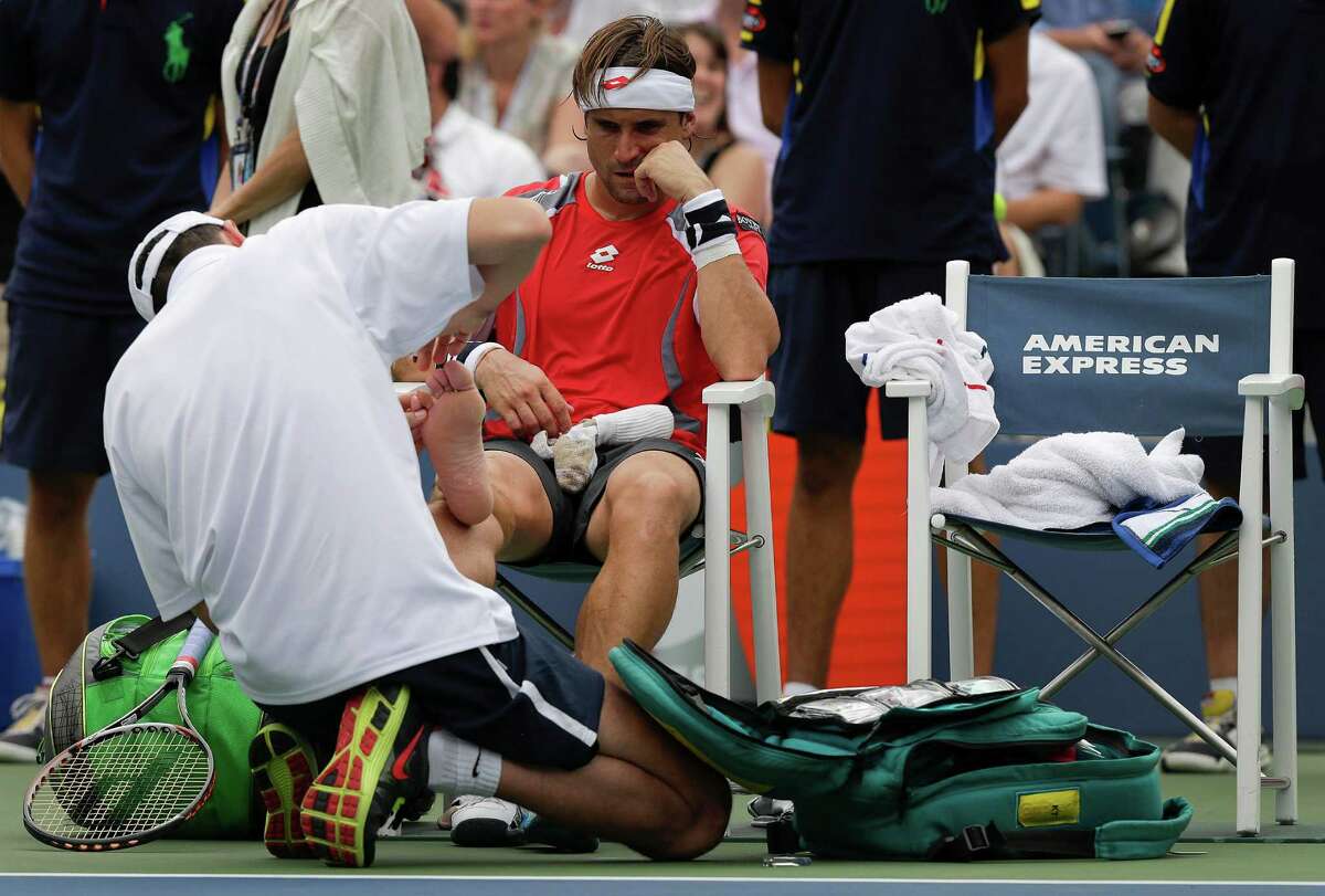 RETRANSMISSION FOR ALTERNATE CROP--Spain's David Ferrer has his right foot worked on during a medical timeout while playing Janko Tipsarevic of Serbia in the quarterfinals during the 2012 US Open tennis tournament, Thursday, Sept. 6, 2012, in New York. (AP Photo/Peter Morgan)