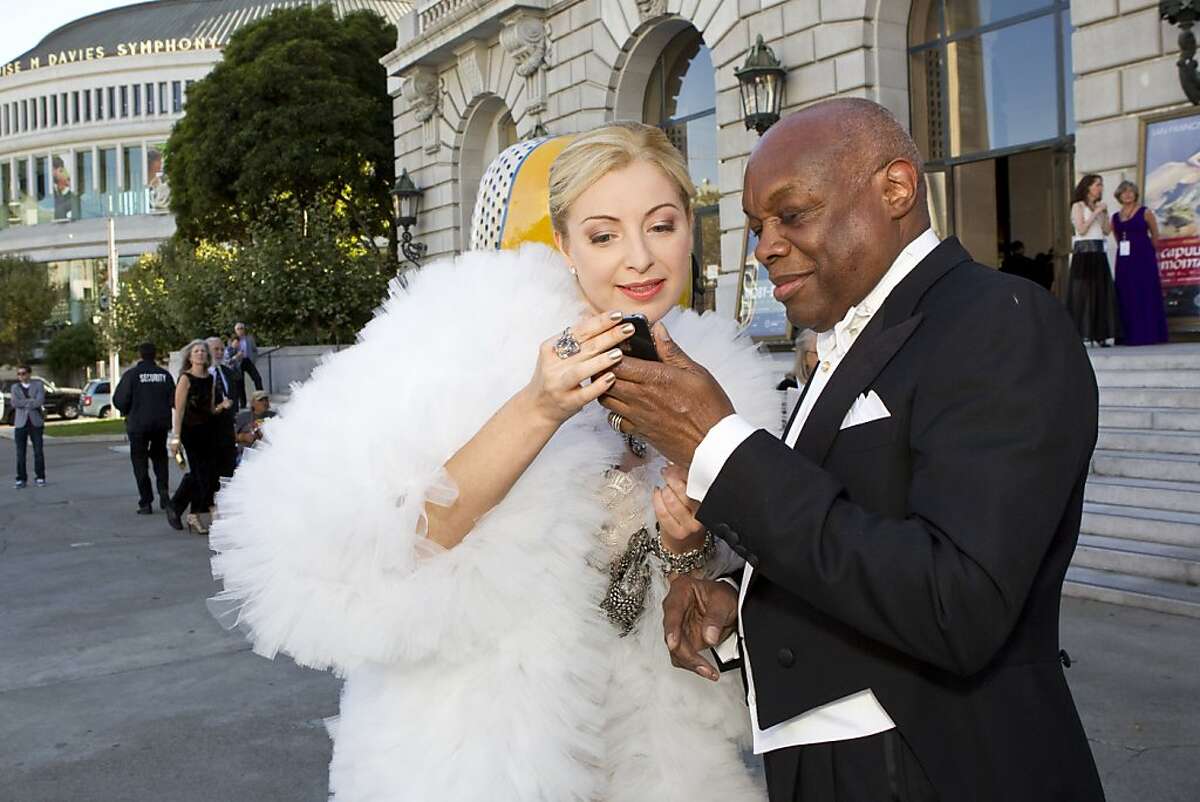 Sonya Molodetskaya looks over cell phone photos taken by a friend with former San Francisco Mayor Willie Brown after arriving at the San Francisco Opera Opening Night Gala at War Memorial Opera House in San Francisco, Calf., on Friday, September 7, 2012.