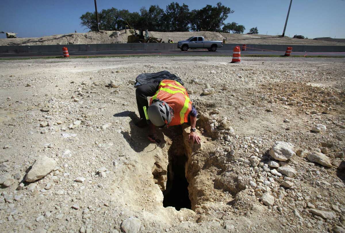 Biologist Jean Krejca inspects a small cave uncovered where TxDOT has been building an underpass on Texas 151 at Loop 1604. Work on the road project has been halted indefinitely.