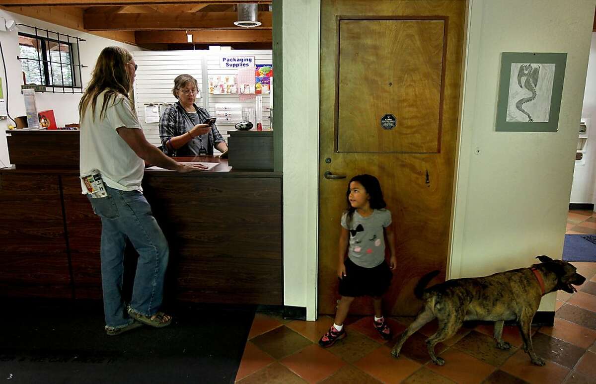 Eliana Murdock, 4-years-old watches over Scrappy as her grandfather Rocky Murdock conducts Post Office business with Carla Williams, a Postmaster Relief employee, on Thursday August 30, 2012, in Canyon, Calif. The town of Canyon is fighting to save it's Post Office from closure, which doubles as a community center. It's the latest Bay Area city to take on the United States Postal Service.