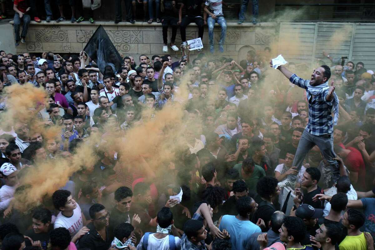 Protesters chant slogans amid orange smoke outside the U.S. embassy in Cairo, Egypt, Tuesday, Sept. 11, 2012. Egyptian protesters, largely ultra conservative Islamists, have climbed the walls of the U.S. embassy in Cairo, went into the courtyard and brought down the flag, replacing it with a black flag with Islamic inscription, in protest of a film deemed offensive of Islam. (AP Photo/Mohammed Abu Zaid)