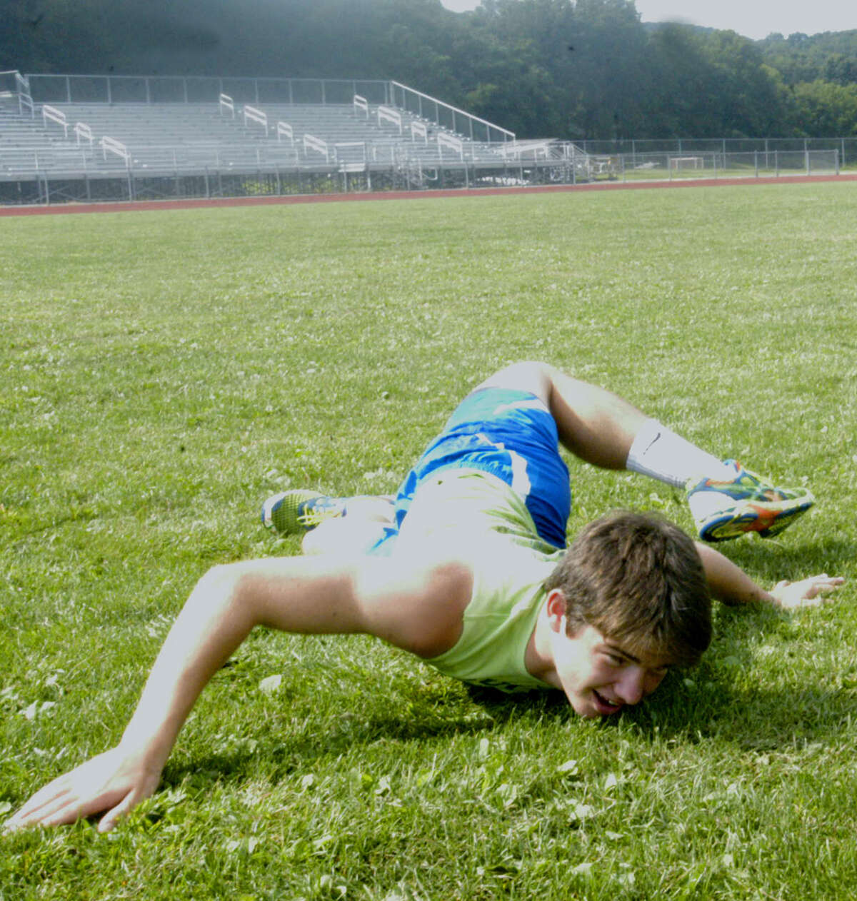 Louis Alhage demonstrates his technique at a challenging stretching exercise employed daily by members of the New Milford High School boys' cross country team, September 2012