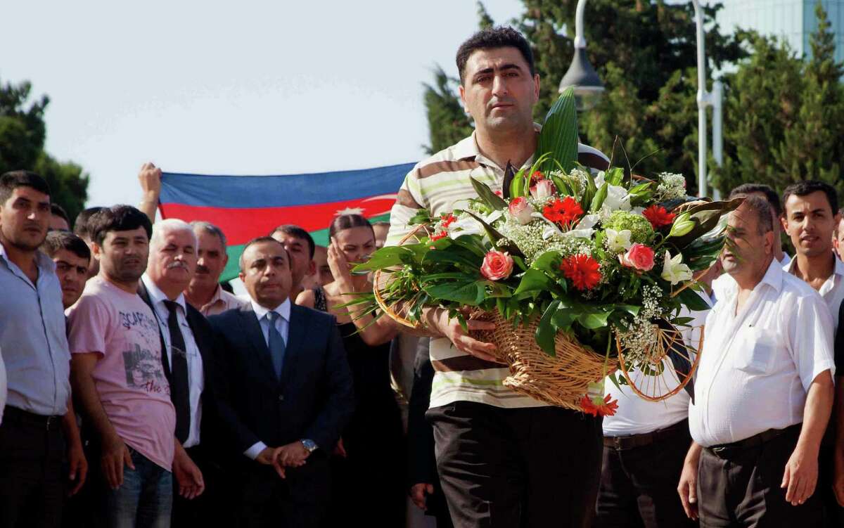 FILE - In this Aug. 31, 2012 file photo, Azerbaijani military officer Ramil Safarov lays flowers at Martyrs' Alley national memorial in the Azerbaijan's capital Baku. Safarov, sentenced to life in prison in Hungary for the murder of an Armenian man, was sent back to his homeland on Aug. 31 and, despite assurances, was immediately pardoned and freed by Azerbaijan's president. (AP Photo/Aziz Karimov, File)