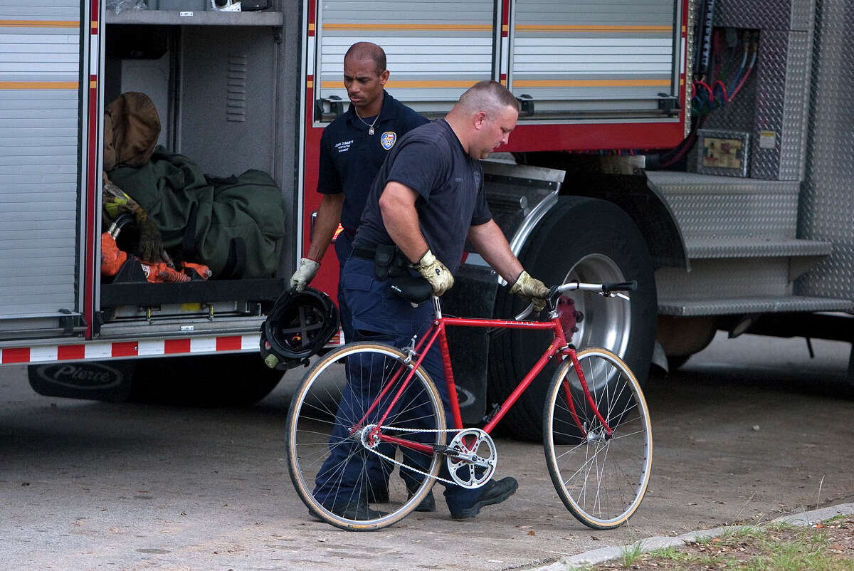 Firefighters wheel a man's bike away after he fell from the Studemont Street Bridge while riding Thursday, Sept. 13, 2012, in Houston. The man was taken to the hospital with severe injuries. (Cody Duty / Houston Chronicle)