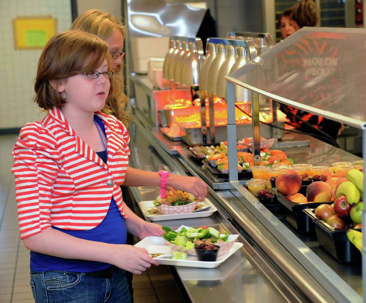 Clara Zonis ,front, and Kelsey Hiscock select food items from the lunch line of the cafeteria at Draper Middle School in Rotterdam, N.Y., Tuesday, Sept. 11, 2012. The leaner, greener school lunches served under new federal standards are getting mixed grades from students. (AP Photo/Hans Pennink)