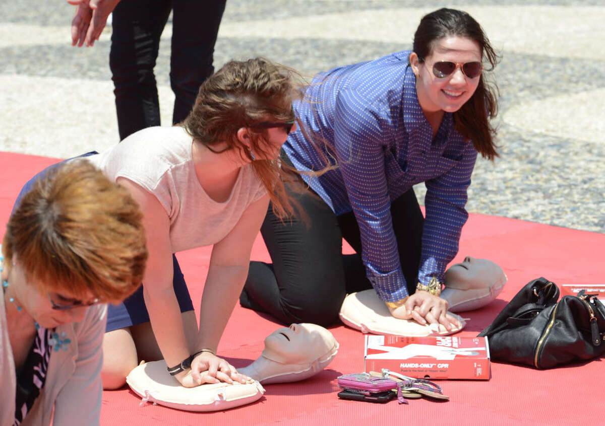 Jeannie Lukin, left and Caitlin Horgan work in unison doing chest compressions to the beat of the song "Stayin' Alive" during The American Heart Association's "Hands Only CPR Tour" stop in Albany, June 11, 2012. (Skip Dickstein/Times Union)