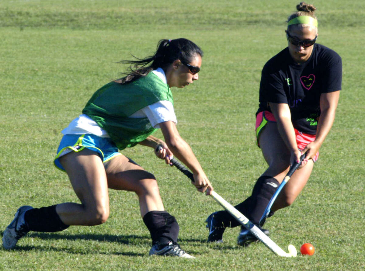 Senior standout Vienna Pallisco, left, tests the ballhandling skills of Green Wave sophomore Lindsey Heaton during a spirited pre-season drill for New Milford High School field hockey. September 2012