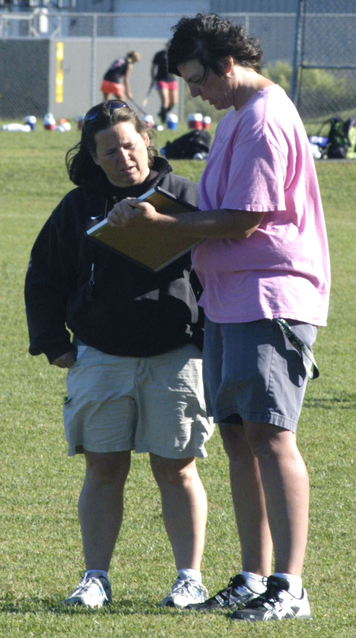 Green Wave coach Dawn Hough, left, and assistant Jen Wyslick plot their strategy during a pre-season drill for New Milford High School field hockey, September 2012