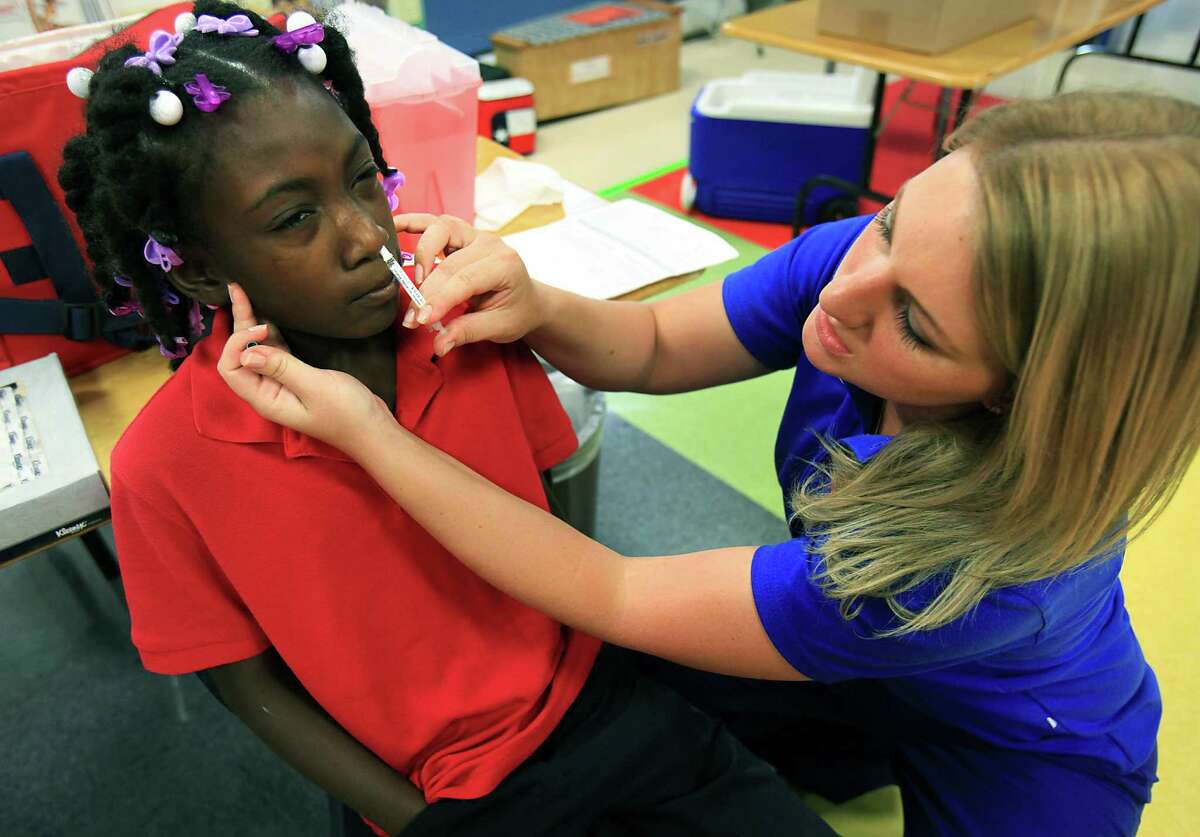 Shauna Shaw, right, of Little Spurs Urgent Care Center, administers the flu vaccine to Torrian Sumlin, a 5th grader at Larkspur Elementary School. Brandi Chastain, Olympian, and World Cup Soccer champion, visited Larkspur Elementary School to support the school's distribution of flu vaccines through the San Antonio Metropolitan Health District. Wednesday, Sept. 19, 2012.