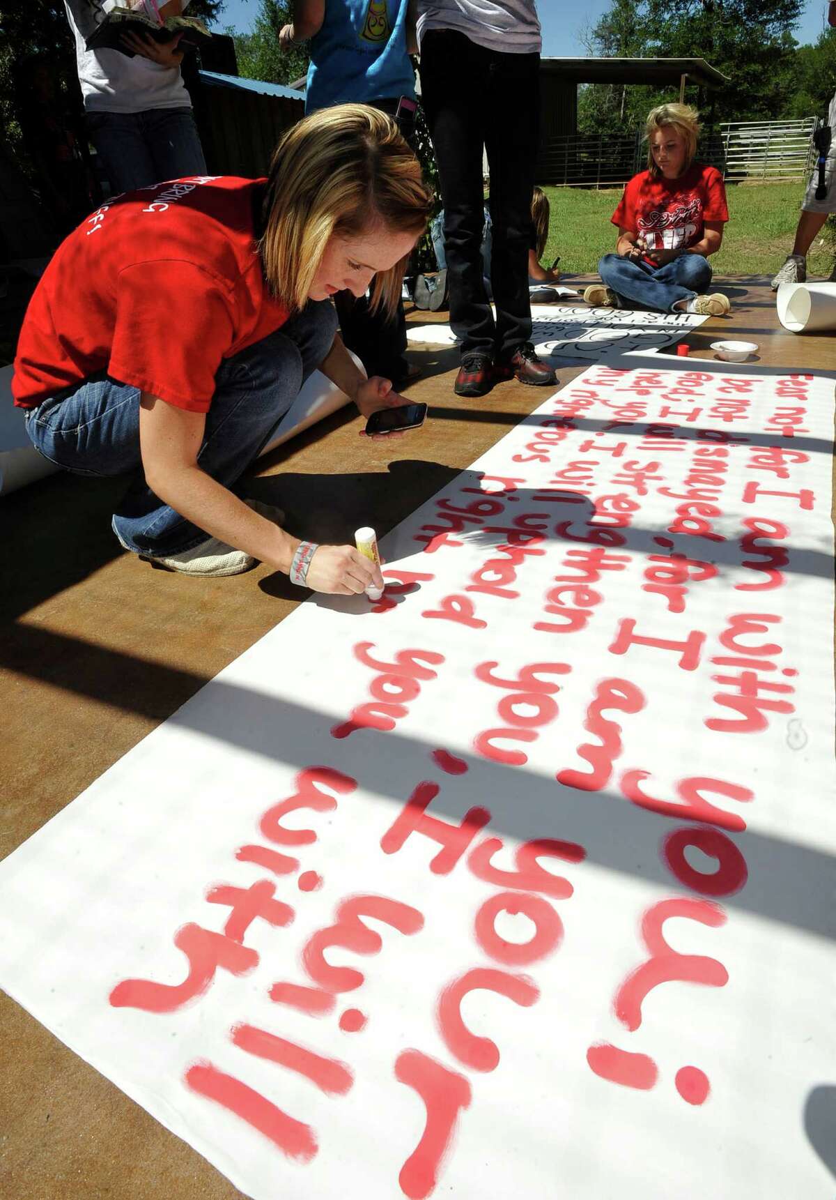 Brooke Coates, left, a cheerleader, paints a long sign on the patio. Kountze cheerleaders, friends and supportive parents who are standing up for their kids and their beliefs, were making signs and painting car windows Wednesday afternoon that will be seen around Kountze in support of the cheerleaders who were told they could not put scripture on their football signs. Each game this season, the Kountze cheerleaders have made Christian-themed run-through signs for the football players. The signs, which featured scripture verses, went viral and have now been stopped by the school district's leaders who were told by a group the signs were offensive and against the separation of church and state. Dave Ryan/The Enterprise