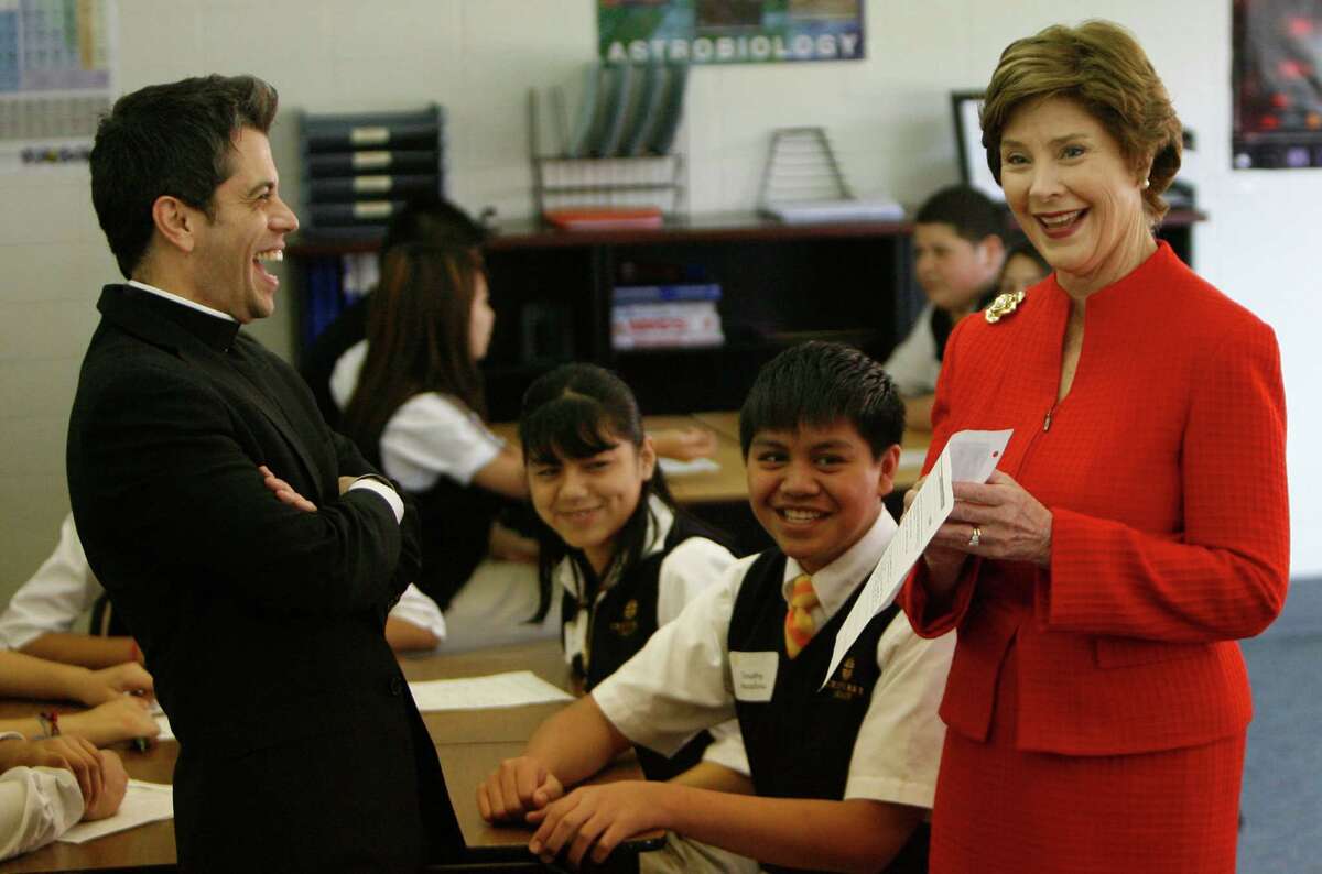 Former First Lady Laura W. Bush, right, and Rev. T.J. Martinez, left, president of Cristo Rey Jesuit College Preparatory School of Houston, react to the mock facebook page of Timothy Macalino, center, in which the 9th-grade student portrays himself as the President of the United States in the facebook page exercise that will be put in a time capsule as part of Andrew Hoyt's English and theology class. Mrs. Bush was visited students of Cristo Rey Jesuit on Thursday, March 11, 2010, in Houston.