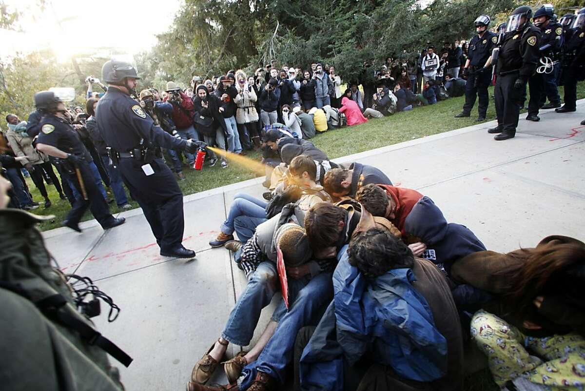 In this Nov. 18, 2011 file photo, University of California, Davis Police Lt. John Pike uses pepper spray to move Occupy UC Davis protesters while blocking their exit from the school's quad in Davis, Calif.