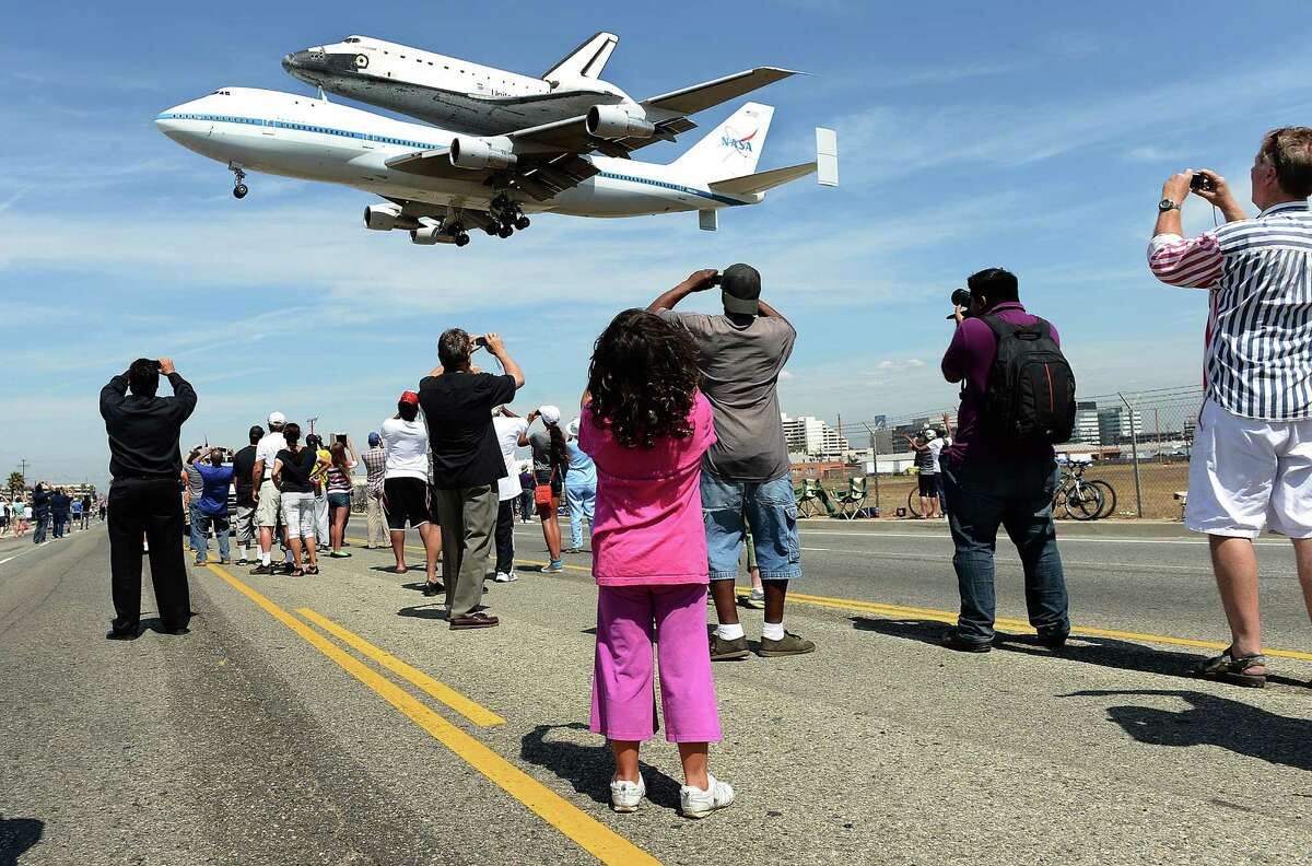 People stand along Aviation Blvd. as the space shuttle Endeavour lands at LAX Friday, September 21, 2012 in Los Angeles, California.
