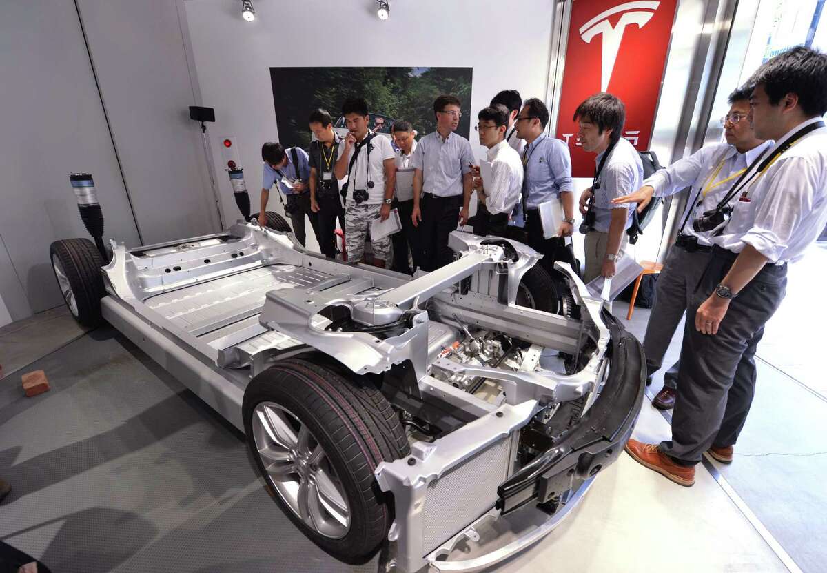 Japanese reporters satnd next to a chassis of US electric vehicle maker Tesla Motors' premium electric Model S sedan during a press preview in Tokyo on August 30, 2012. Model S is the first premium sedan designed from the ground up to take full advantage of electric vehicle architecture. AFP PHOTO / KAZUHIRO NOGIKAZUHIRO NOGI/AFP/GettyImages (AFP/Getty Images)