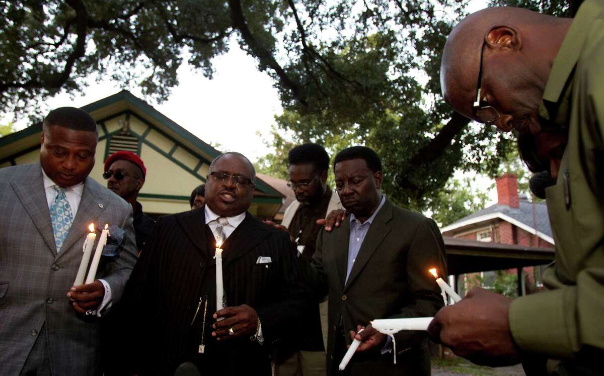 The Rev. Ronald Smith, second from left, leads a prayer on Tuesday evening outside the personal care home where Brian Claunch, a mentally ill double amputee, was shot and killed by a Houston police officer last week.