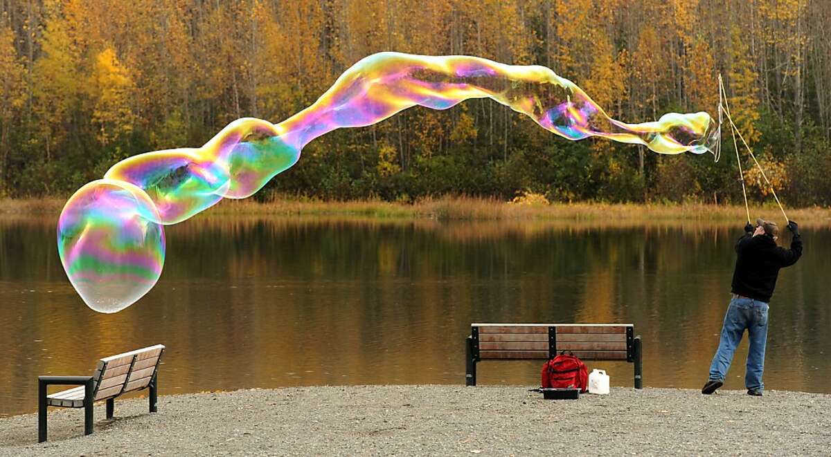 Jay Hiner creates giant bubbles using a home-made wand and non-toxic solution Tuesday, Sept. 25, 2012, at Cheney Lake in east Anchorage, Alaska.