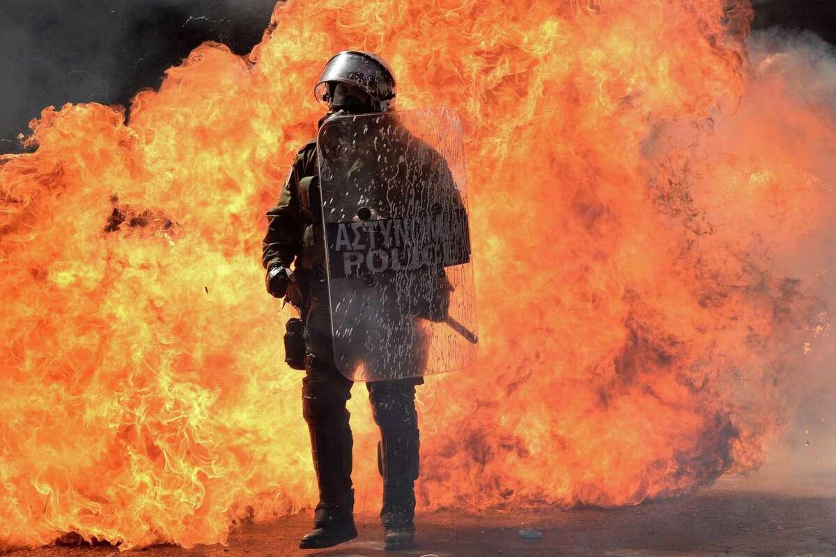 A riot police officer stands in front of burning firebombs on September 26, 2012 in Athens during a 24-hours general strike. Police in Athens clashed with hooded youths throwing firebombs on the sidelines of a large demonstration against a new round of austerity cuts. AFP PHOTO / ARIS MESSINISARIS MESSINIS/AFP/GettyImages