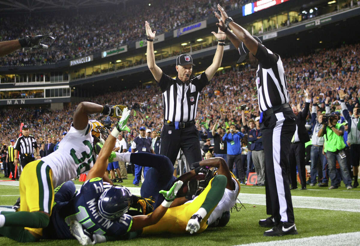 Side Judge Lance Easley, center, looks at back judge Derrick Rhone-Dunn as Easley calls a Seattle Seahawks touchdown catch by Golden Tate and Rhone-Dunn says the catch is no good in the final second of the Seattle Seahawks and Green Bay Packers game Monday Night Football game on September 24, 2012 at CenturyLink FIeld in Seattle. The controversial call put the Seahawks over the Packers to win 14 to 12.